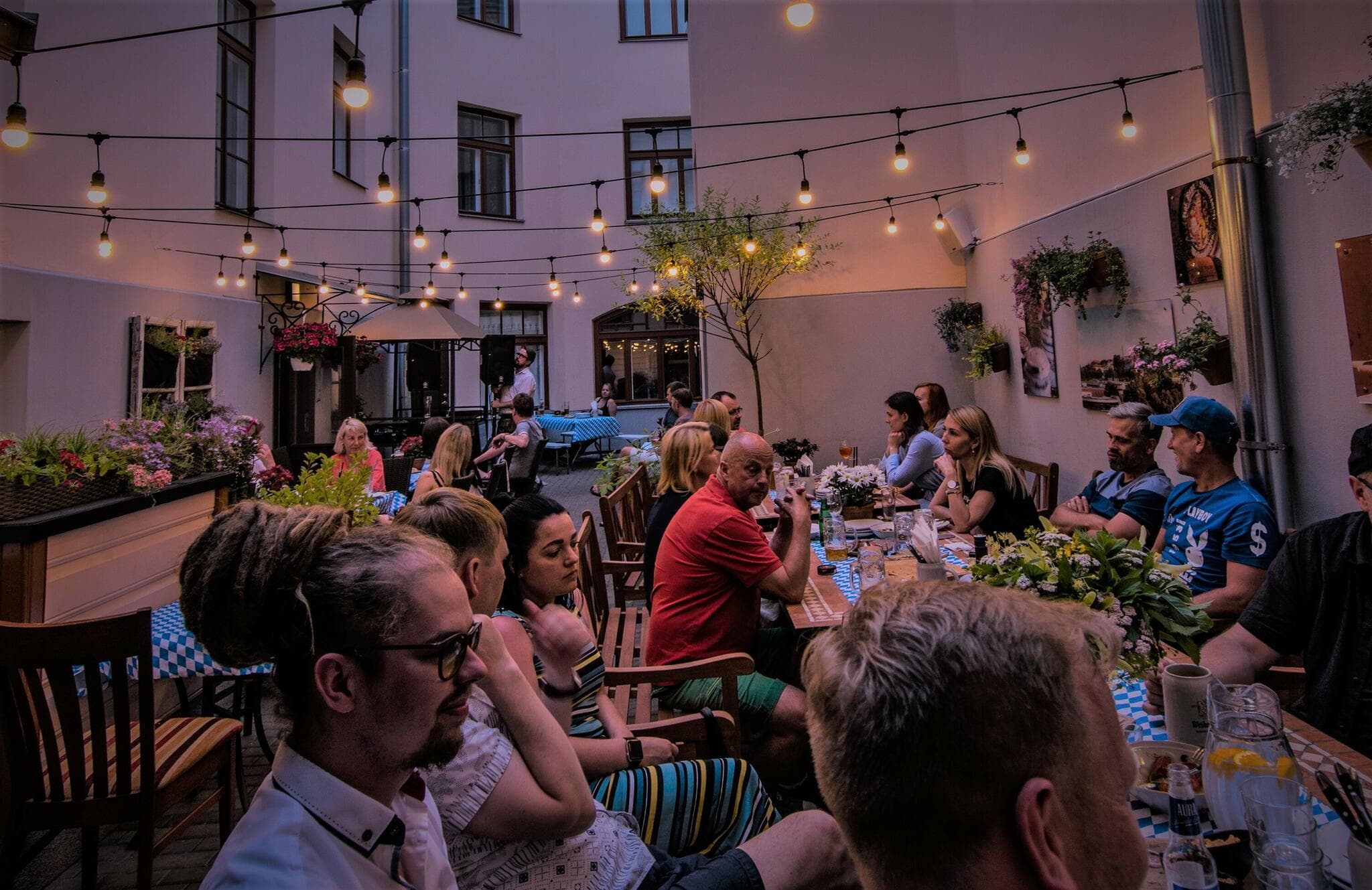 Õhtune Biergarten tulede all, täis külalisi